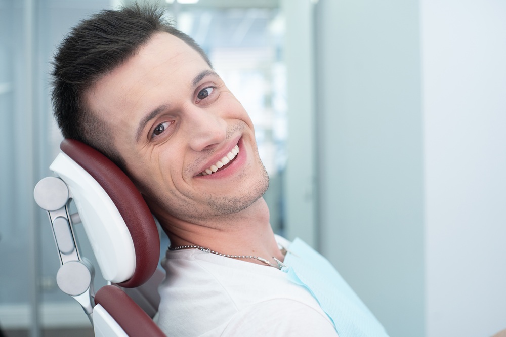 Dental patient glancing back with a confident smile while seated in the treatment chair