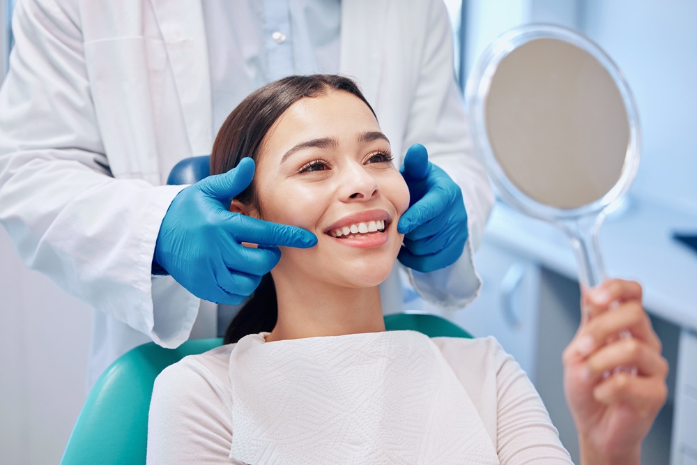 All-On-X Consultation in Irvine: Patient Viewing Her Smile in the Mirror Dental patient viewing her smile in a hand mirror during her dental visit