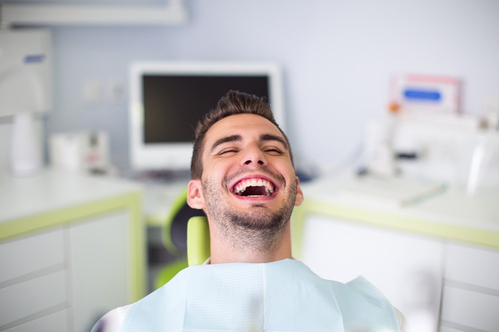 Dental patient laughing with a wide, healthy smile in the treatment chair at our Irvine dental office