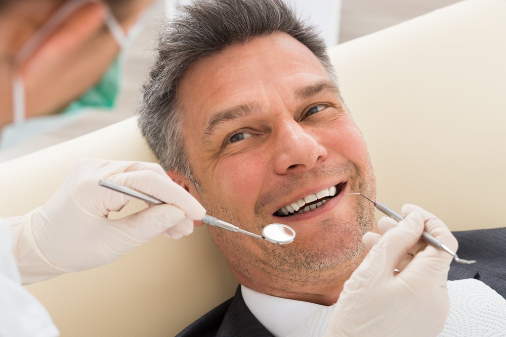 Dental provider examining a patient's teeth using a mirror and explorer