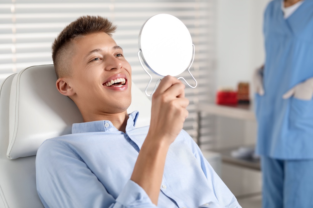 Irvine Dental Patient Reviewing His Smile in the Treatment Chair Dental patient reviewing his smile using a hand mirror in the dental chair