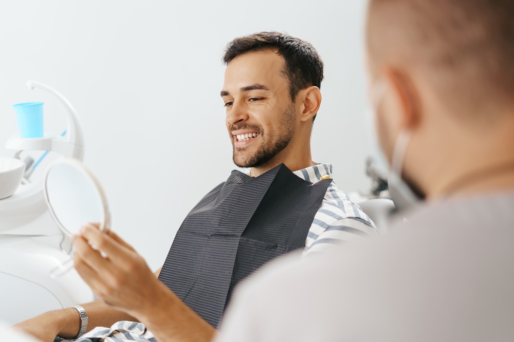Dental patient reviewing his smile with a hand mirror at our Irvine dental office