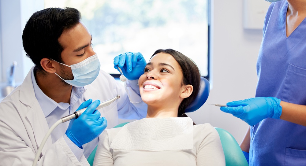 Dentist preparing dental instruments to begin a procedure with a smiling patient at our Irvine dental office
