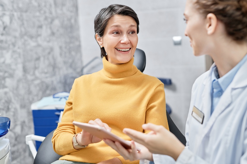 Irvine Dental Patient Consultation: Discussing Treatment Options Dental patient in Irvine discussing treatment options with a team member using a tablet