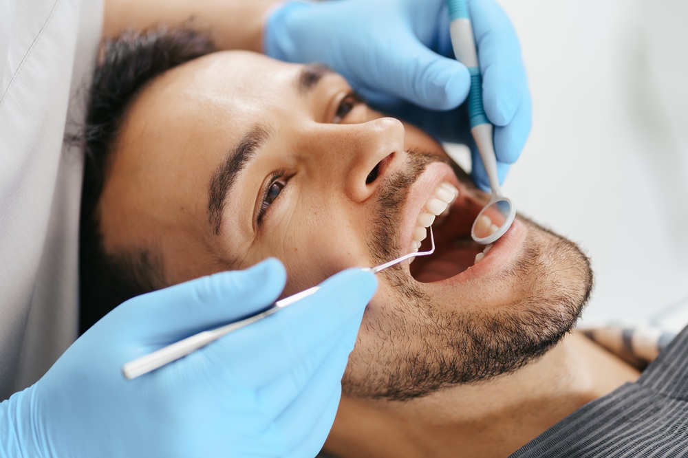 Close-up of a patient's teeth being examined with a dental mirror and explorer