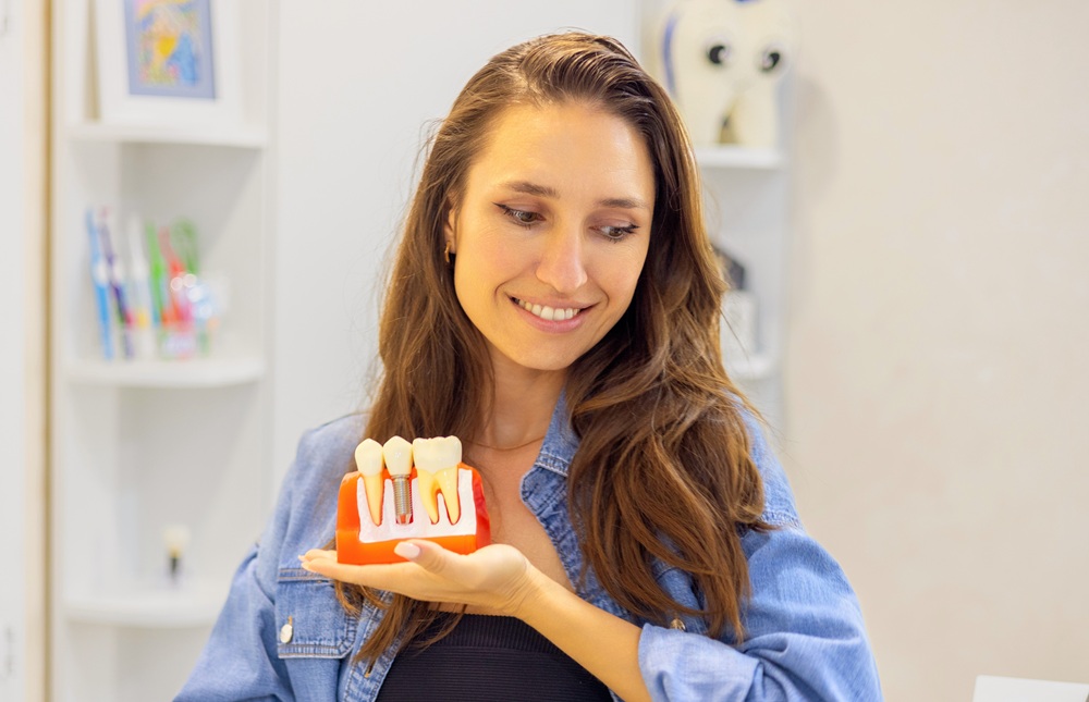 Irvine Dental Implant Patient, Reviewing Her Tooth Replacement Options Patient holding a dental implant model during a consultation at our Irvine dental office