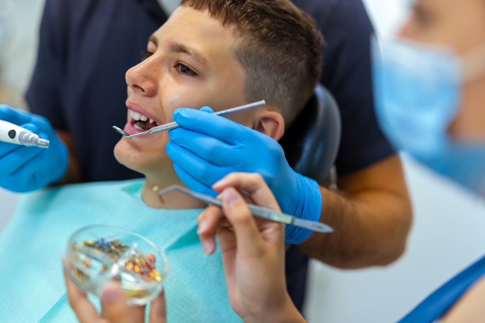 Young dental patient having his teeth examined with dental instruments